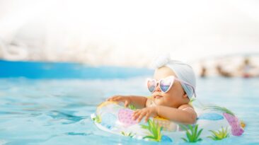 Cute funny toddler girl in colorful swimsuit and sunglasses rela