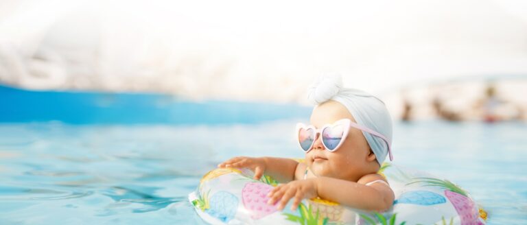 Cute funny toddler girl in colorful swimsuit and sunglasses rela