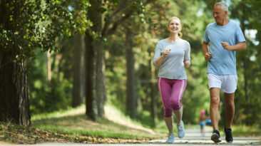 Active and healthy aged couple running in natural environment on summer morning