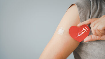 senior woman holding red heart shape with syringe and showing her arm with bandage after got vaccinated or inoculation due to spread of corona virus, population, social or herd immunity concept