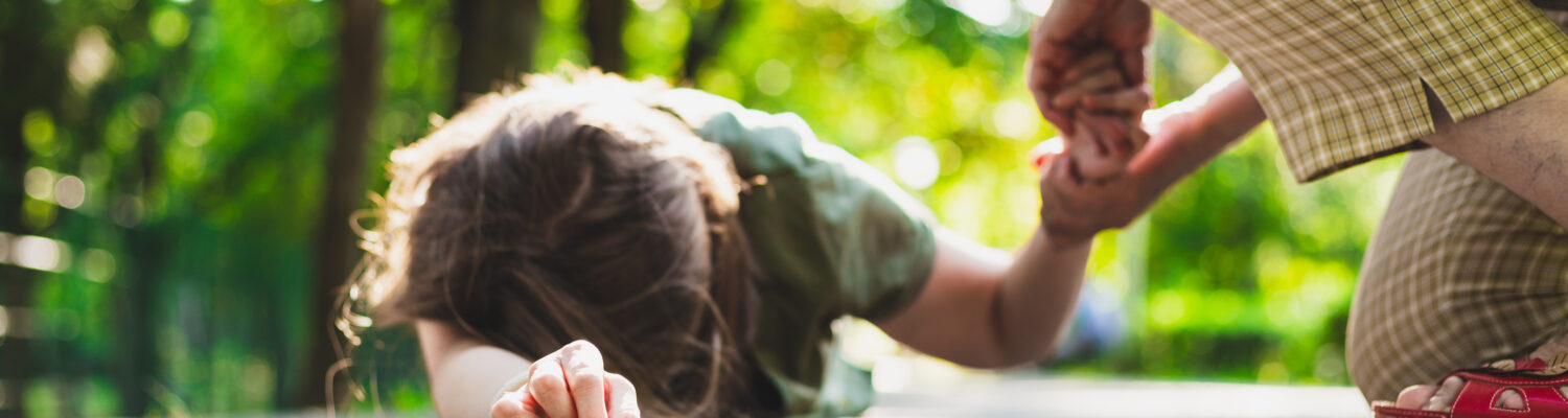 Fainted girl helped by an old woman – Teenager lying on the ground while receiving support from an elder