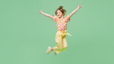 Full body happy little child kid girl 6-7 years old wear casual clothes jump high raise up hands isolated on plain pastel green background studio portrait. Mother's Day love family lifestyle concept