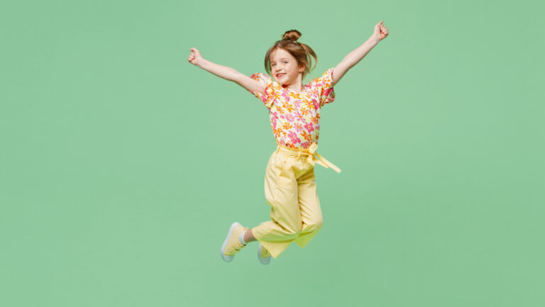 Full body happy little child kid girl 6-7 years old wear casual clothes jump high raise up hands isolated on plain pastel green background studio portrait. Mother's Day love family lifestyle concept