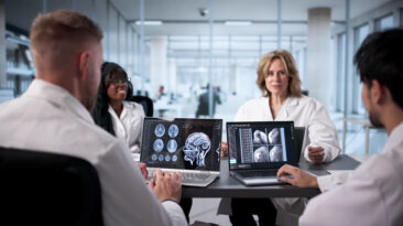 Neurologist At Hospital Analyzing Brain Scan On Computer Screen Carefully.